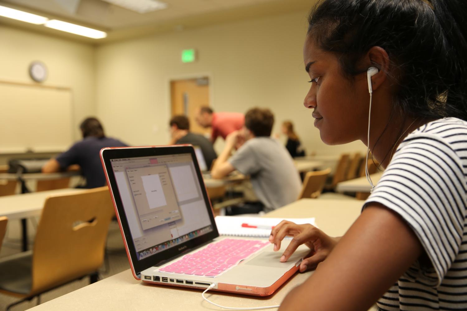 A student focusing intently on a software program on her laptop during class.